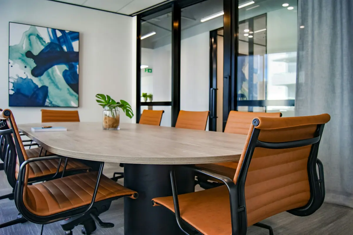 Sala de reunião com mesa oval e cadeiras em couro caramelo